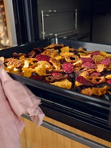 Link useful oven features, open oven with tray of colourful airfried vegetables  