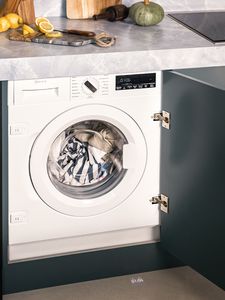 A high angle view onto a washing machine in a cupboard underneath a kitchen countertop.