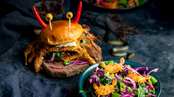 Finished recipe with crab burger next to salad in bowl