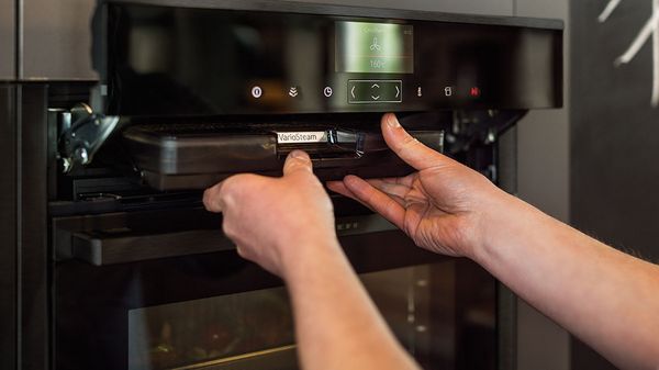 Woman removing steam tray from NEFF Steam Oven