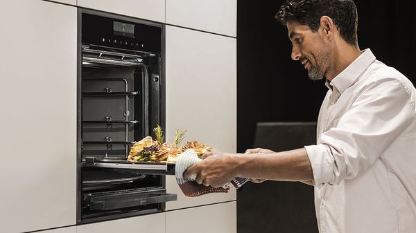 Woman putting food in NEFF Slide&Hide Oven