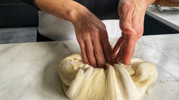 Leg het deeg op een schoon werkblad en kneed het stevig totdat alle lucht eruit is. Vouw met de palm van je handen het deeg naar binnen en vorm een bal.