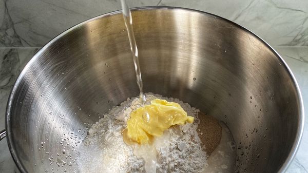 Doe de bloem in een kom en voeg aan de ene kant het zout toe en aan de andere kant het gist. Voeg de boter toe en vermeng het geheel met je handen.