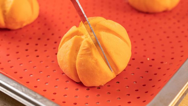 Person adding lines to bao bun tops to make them look like pumpkin ridges