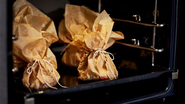 Parchment packets on a backing sheet in the oven.