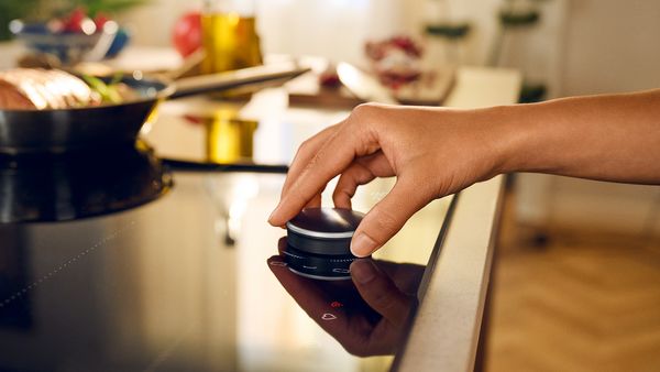 Mano femminile che posiziona Twist Pad Flex sul piano cottura, ripresa di lato  