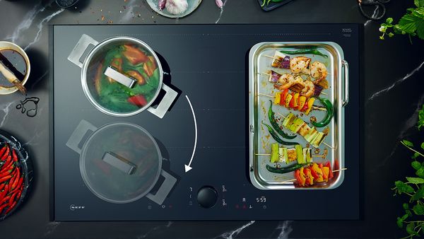 Cooktop with pot and griddle pan and colourful vegetables showing Intuitive Flex Zone 
