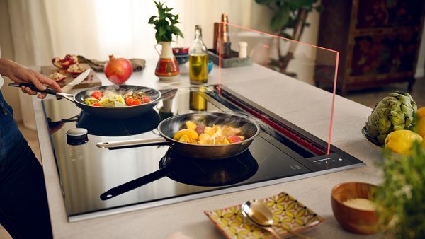 Glassdraft afzuigkap weergegeven met verschillende gerechten die op de kookplaat 