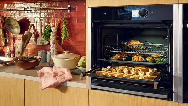 Video della funzione Slide&Hide su forno N90 con sportello aperto, con alimenti in cottura su 3 livelli  