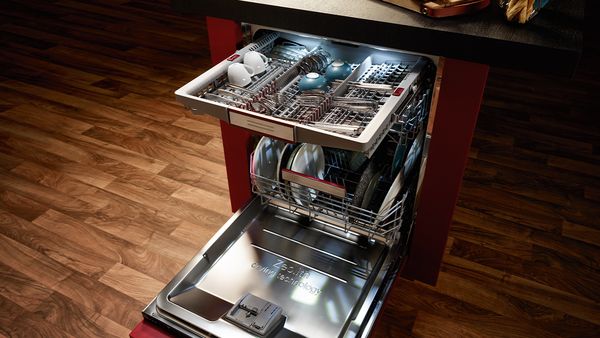 A free-standing, open dishwasher with a cutlery drawer pulled out at the top