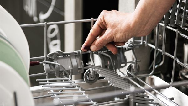 A close-up of a hand folding down flip tines in a dishwasher basket