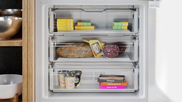 A look into a freezer with three compartments, all filled with groceries with no frost in sight