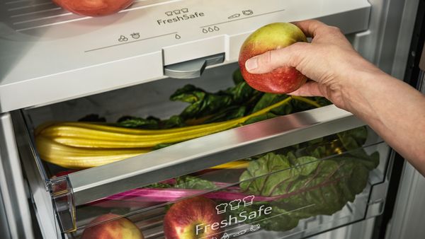 A hand removing an apple from the Fresh Safe drawer of a fridge
