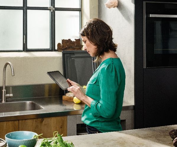 Woman using tablet in the kitchen to register appliances