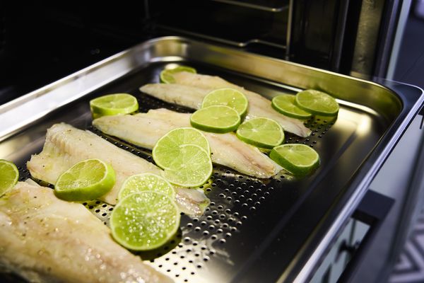 Le poisson est décoré avec du citron vert sur la plaque du four