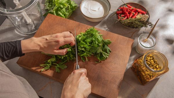 someone chopping parsley on a wooden board