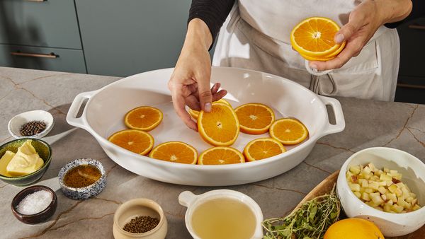 Placing orange slices into the baking dish