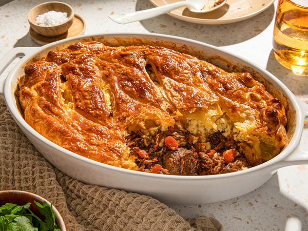 Steak and Ale Pie with a golden brown crust served in a baking dish on a table.