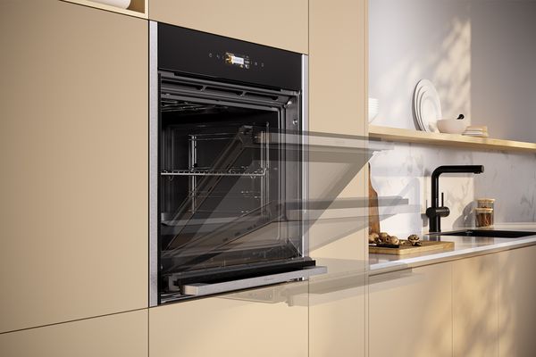 Black NEFF oven with open door, installed in a modern kitchen.