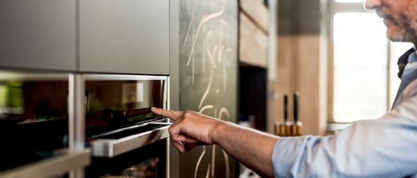 Man using NEFF oven control panel in a kitchen scene
