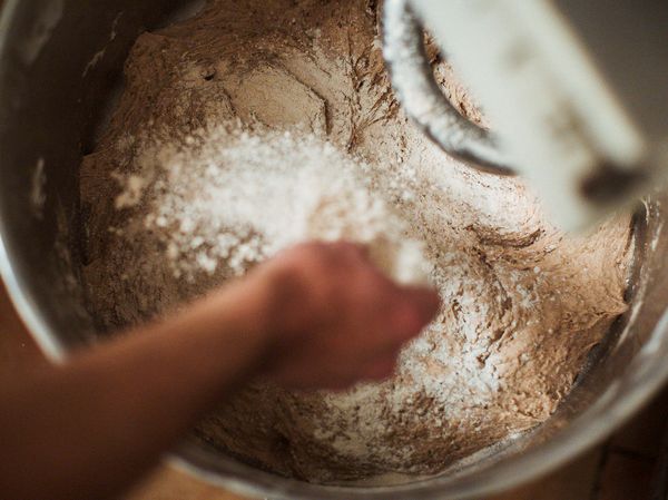 Person adding flour to bread dough mixture