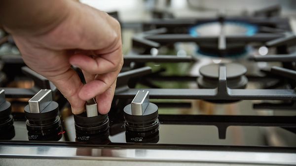 Hand using control dials on NEFF hob