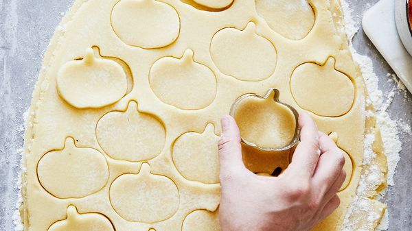 Person using pumpkin shaped cutter on dough