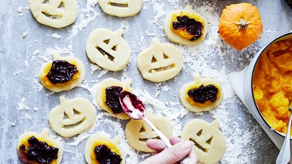 Person spooning pumpkin puree and then blueberry mixture on top of pumpkin shaped dough