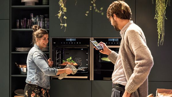 Молодая пара готовит ужин с помощью техники NEFF и приложения Home Connect.