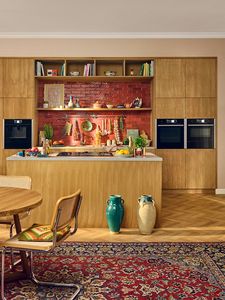 Wide shot of warm wooden kitchen with red tiles 