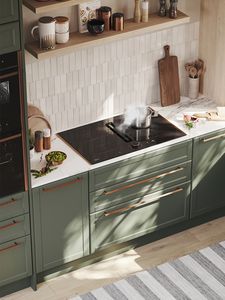 View of a modern olive green kitchen with a hob with integrated ventilation installed under shelves on the wall