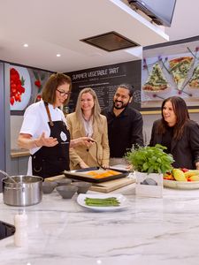 A group of people gathered around a food counter, engaging in conversation while serving themselves from various dishes.  