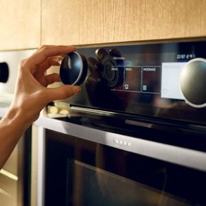 Een hand die een Twist Pad Flex®-knop op een moderne oven draait.