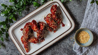 Crispy fried chicken pieces served with potato wedges and a small bowl of sauce.     
