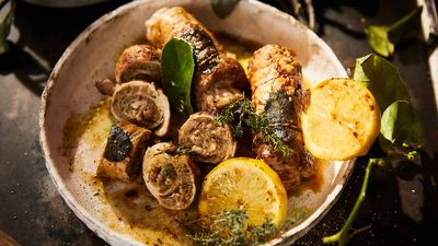 Sliced and stuffed pork loin, topped with some thyme and lemon in a bowl
