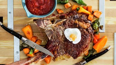 A medium rib-eye steak, garnished with some oven vegetables
