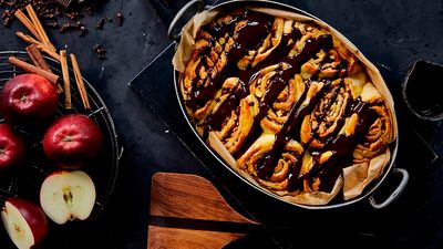 Cinnamon rolls topped with dark chocolate in a metallic baking pan