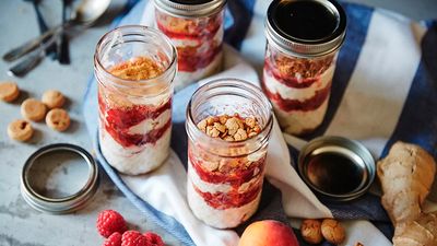 Four jars of layered dessert with raspberries, almond cookie crumble and mascarpone