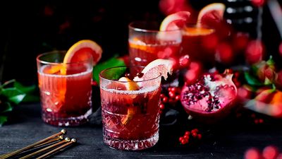Some longdrink glasses of rose mulled wine with added mandarine slices and pomegranate seeds