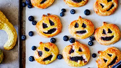 Some Halloween pasties, cuted out as pumpkin shapes and garnished with blueberries