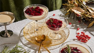 Two glasses of cinnamon pannacotta with mulled wine cherries on a decorated table