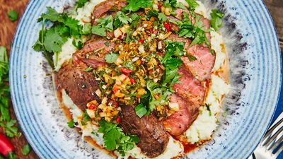 Sliced roast beef, placed on plate and garnished with chimichurri sauce and root parsley