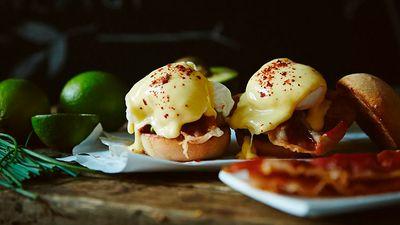 Two english, sliced muffins, topped with serrano ham and two poached eggs