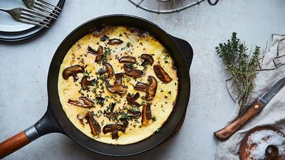 A porcini mushroom omelette, garnished with thyme leaves in a black frying pan