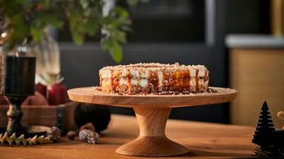 A caramel and hazelnutt brittle cheesecake on a wooden cake tin