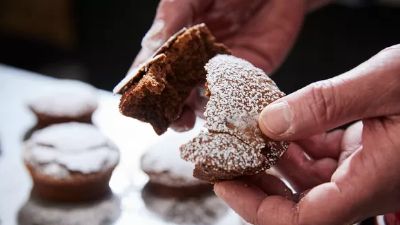 Mano con dolce al cioccolato spolverato di zucchero. 