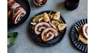 Gebrande varkensbuik, ananas en groenten op zwarte borden met bierflessen.