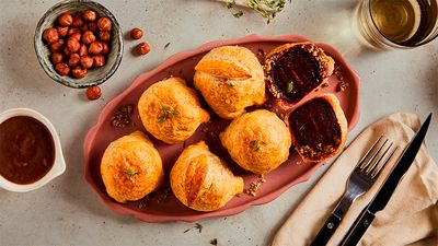 A pink tray contains puff pastry balls arranged on an elegantly laid table