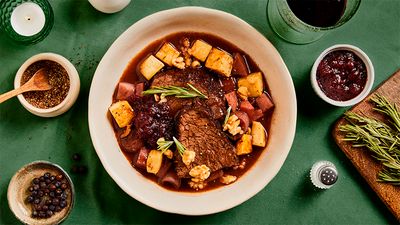 A plate with a recipe of meat in sauce on a green tablecloth