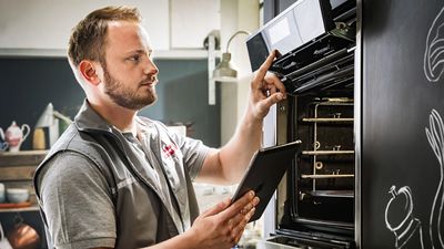 Tecnico NEFF mentre ripara un forno da incasso in una cucina.